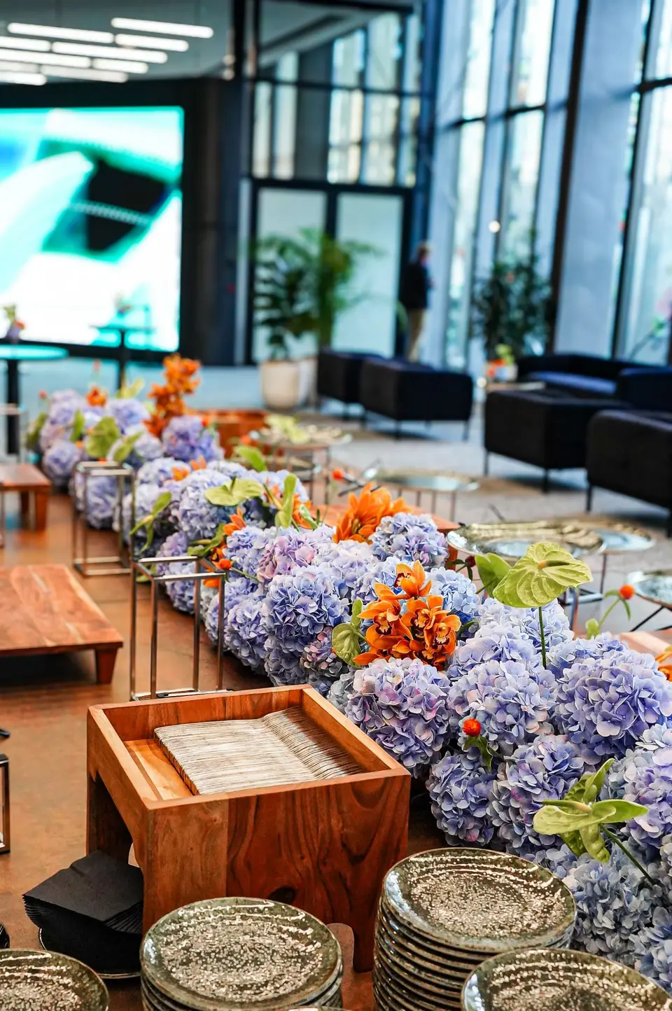 Blue hydrangea, orange orchid and green anthurium runner along a corporate event buffet in Auckland