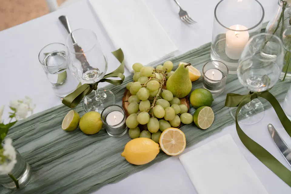 Green grapes, pears and citrus styled on a sage table runner