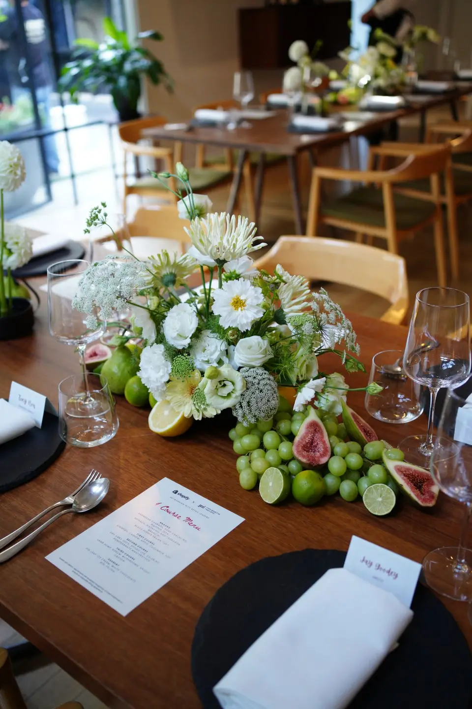Dinner table centrepiece of white flowers with figs, grapes and limes for a private event in Auckland