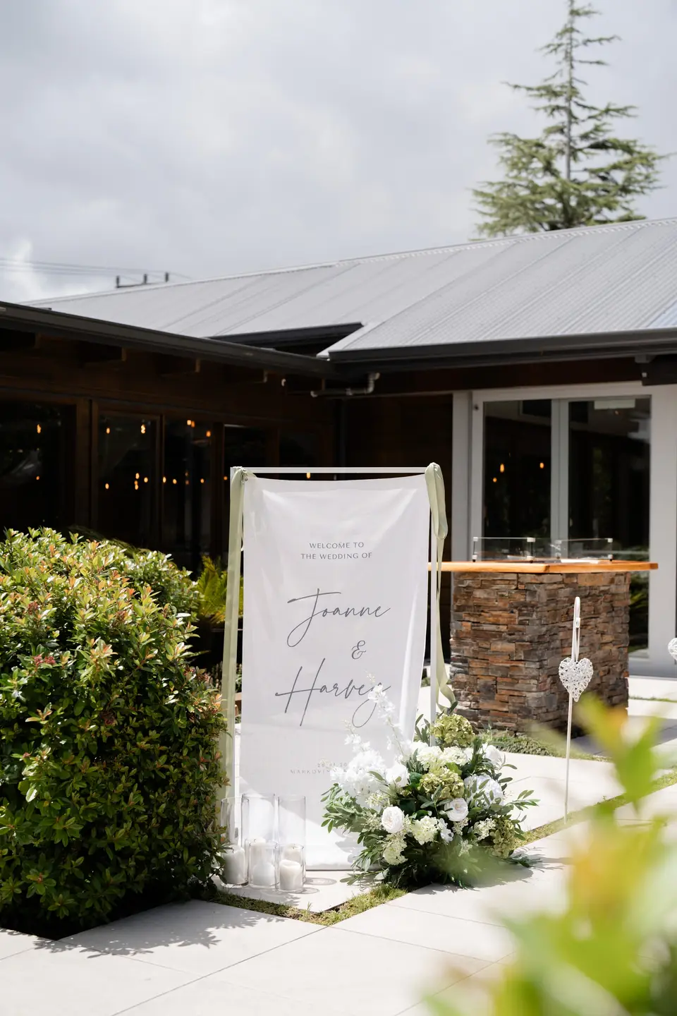 Welcome sign for Joanne and Harvey with a white hydrangea floral arrangement