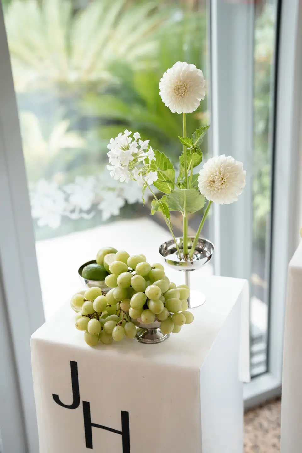 White dahlias in a silver coupe on the monogrammed welcome plinth